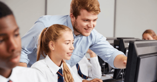 Teacher instructing a young girl how to use her computer